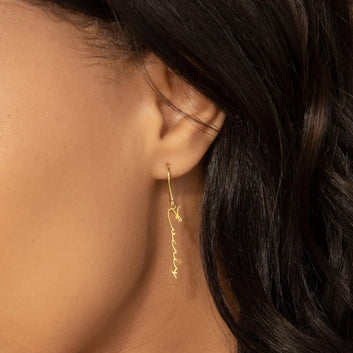Gold earring worn by a person with dark hair.