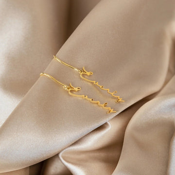 Gold bracelet with star design on a beige fabric background