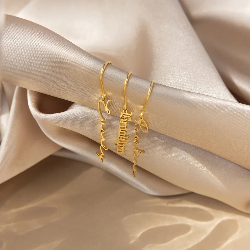 Gold bracelets with engraved text on a beige satin background