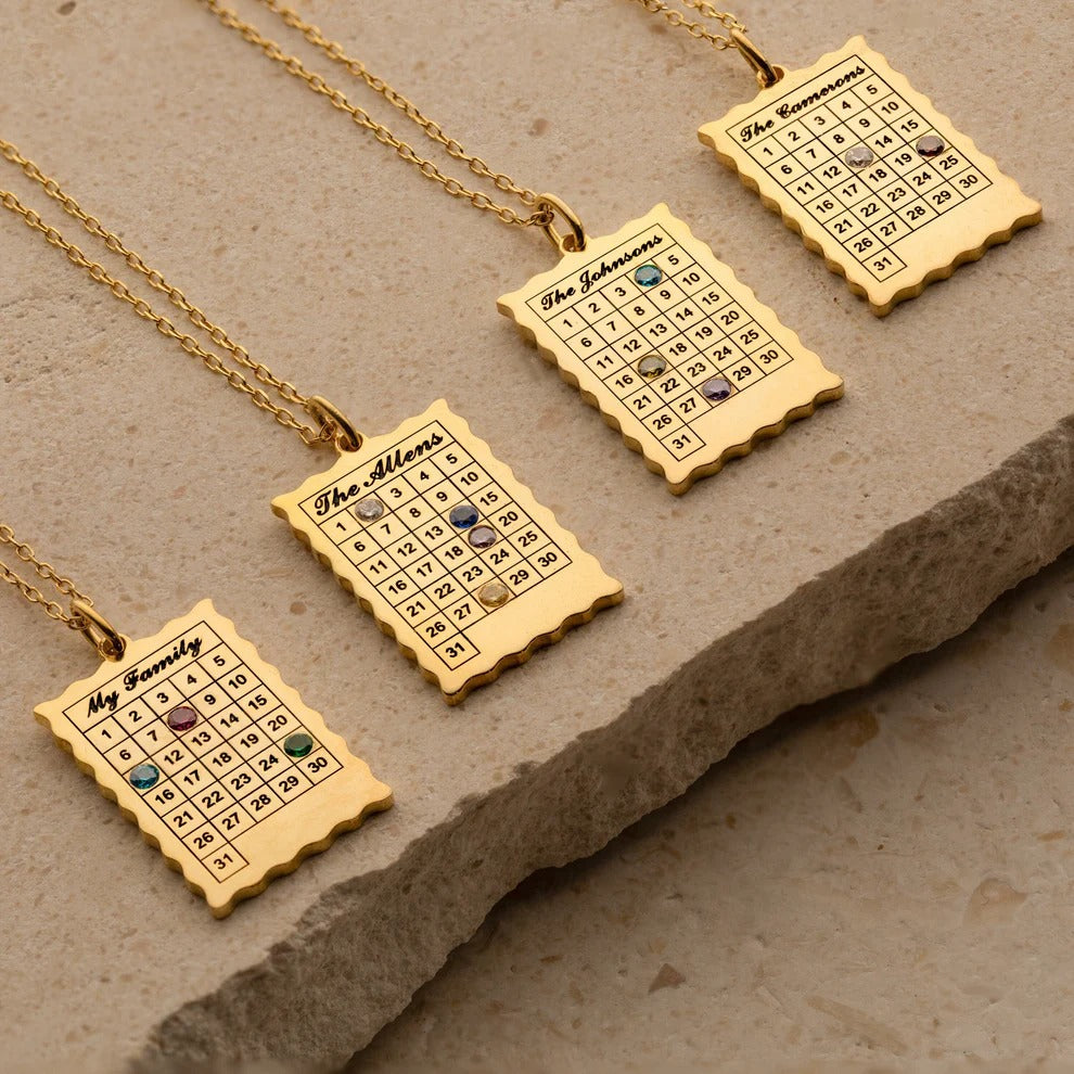 Gold necklaces with engraved calendar pendants on a stone surface