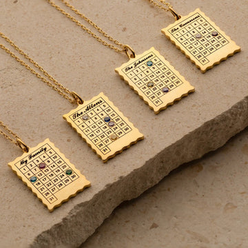 Gold necklaces with engraved calendar pendants on a stone surface