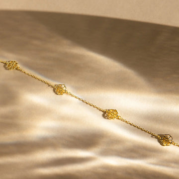 Gold bracelet with floral designs on a beige background