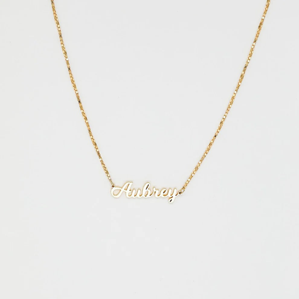 Gold necklace with 'Anbrey' pendant on a light gray background
