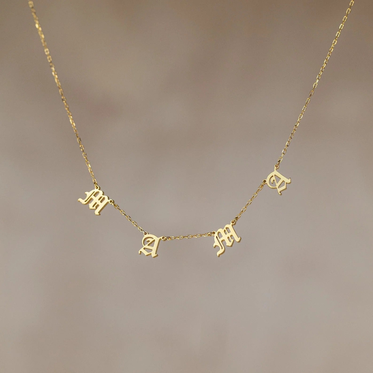 Gold necklace with letter pendants on a blurred background