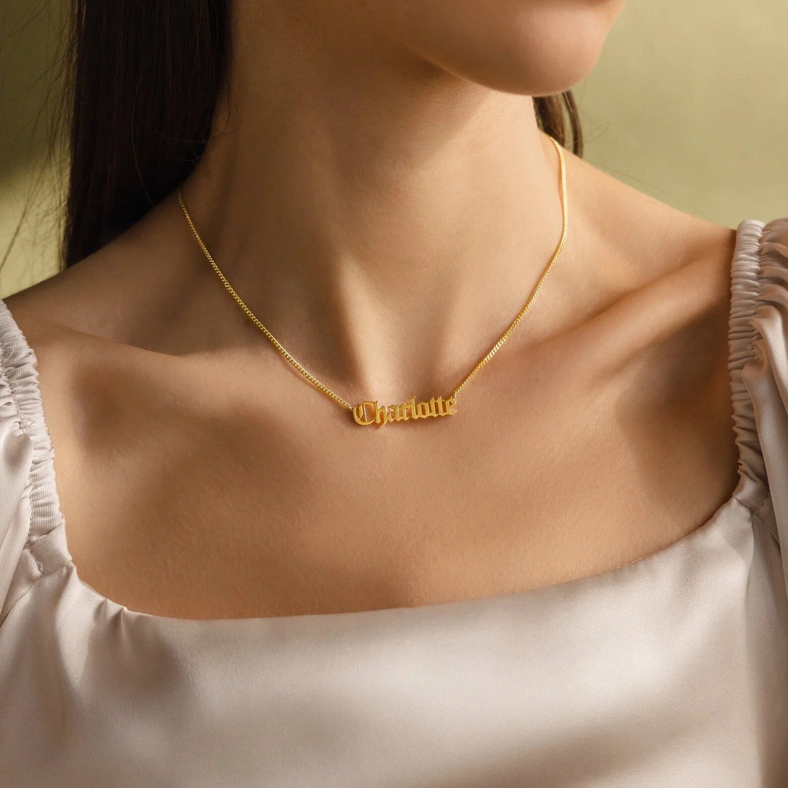 Gold name necklace on a person with a soft background