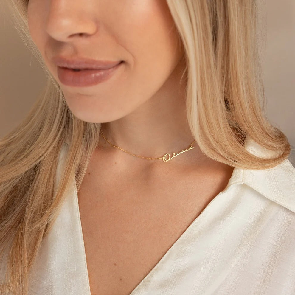 Close-up of a woman wearing a gold necklace with 'Olivia' engraved on it.