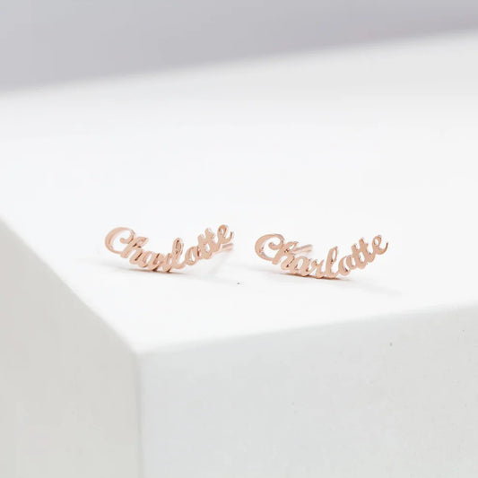 Rose gold 'Charlotte' name earrings on a white background