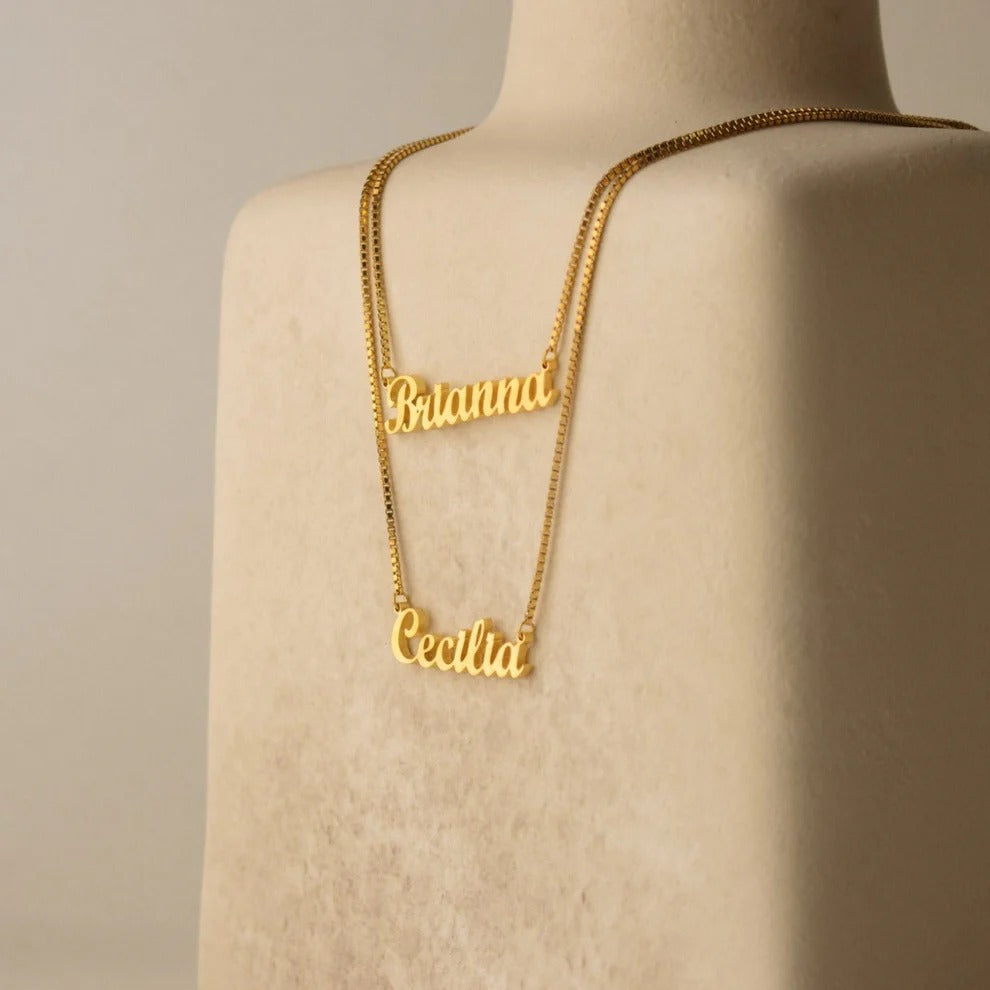 Gold name necklace on a mannequin with a beige background
