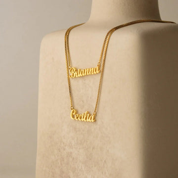 Gold name necklace on a mannequin with a beige background