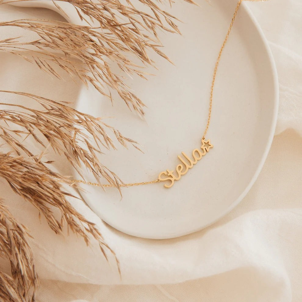 Gold 'Stella' necklace on a neutral background with dried grasses