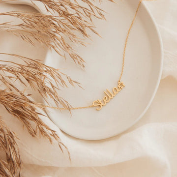 Gold 'Stella' necklace on a neutral background with dried grasses