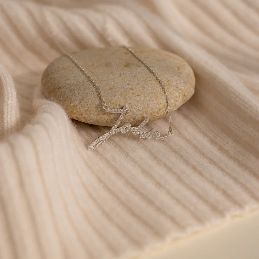 Necklace draped over a smooth stone on sand