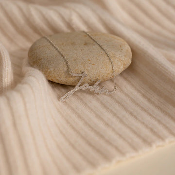 Necklace draped over a smooth stone on sand