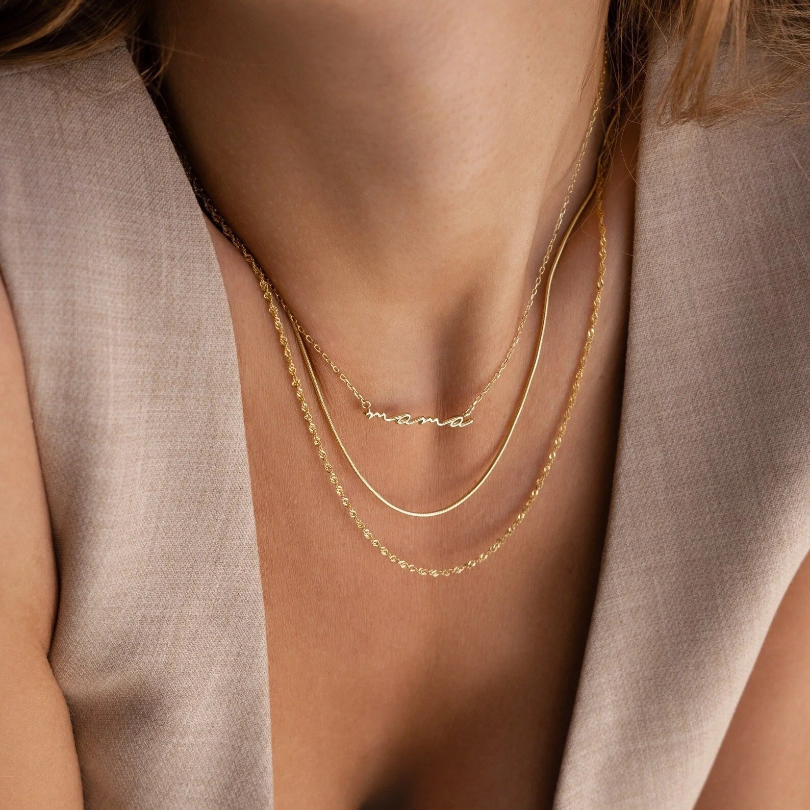 Gold necklaces on a person wearing a light brown top
