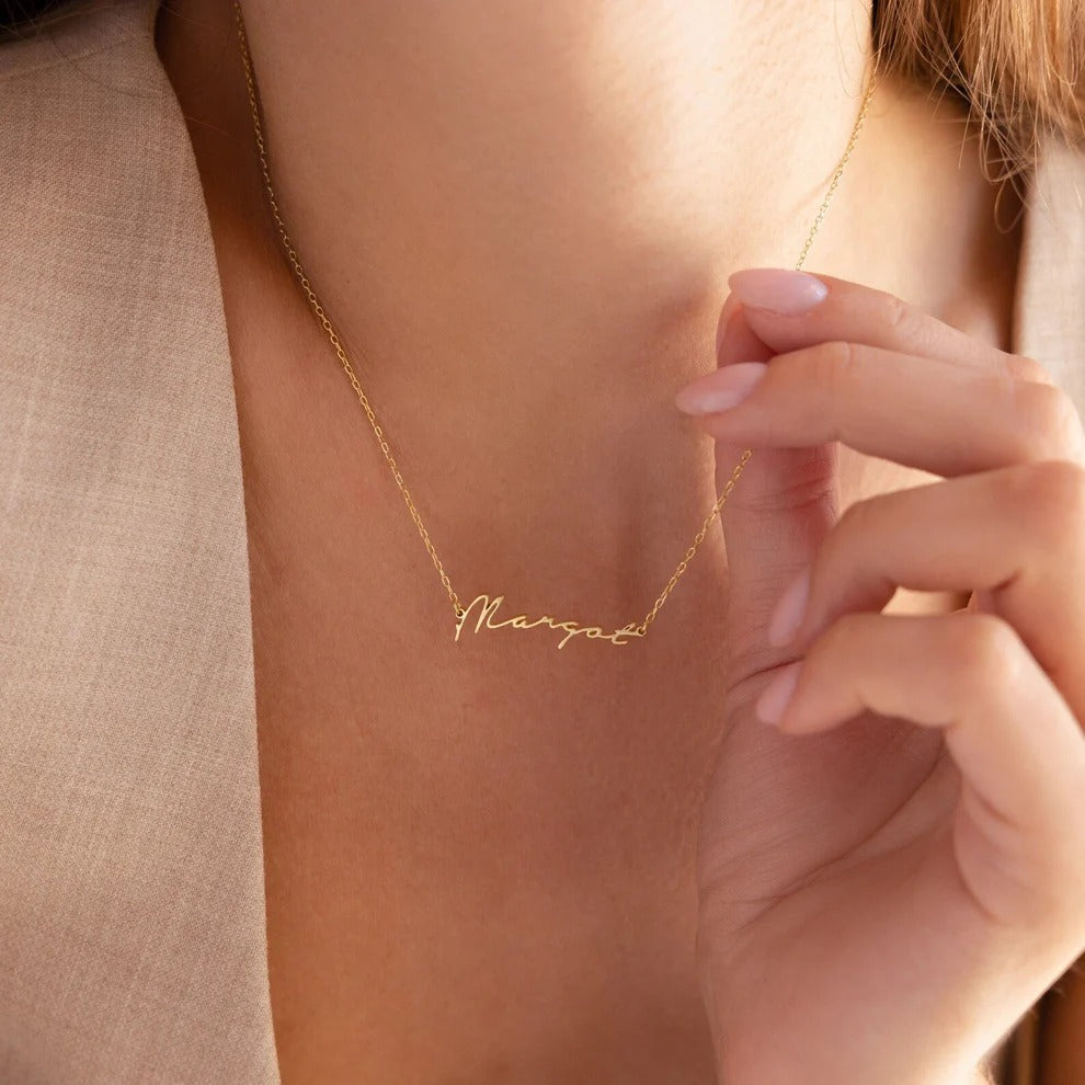 Gold necklace with 'Margot' engraving on a person's neck