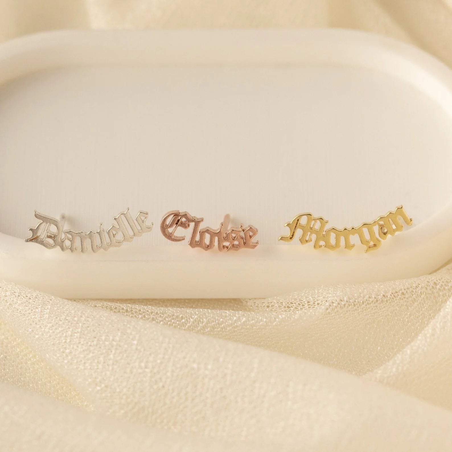 Three gold nameplates with names 'Danielle', 'Cloise', and 'Morgan' on a beige background.