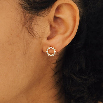 Close-up of an ear wearing a silver hoop earring with small stones.