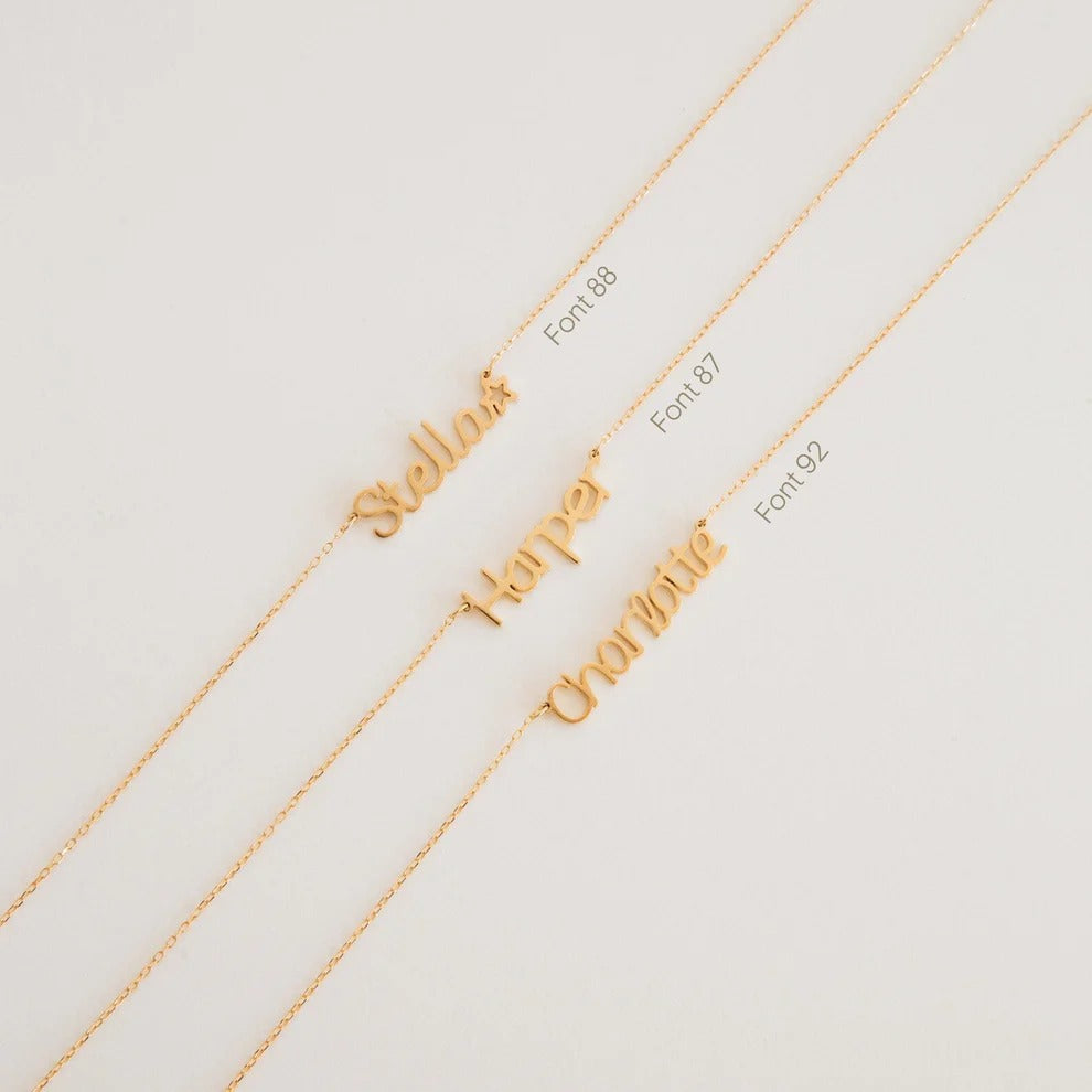 Gold necklaces with different name engravings on a light background