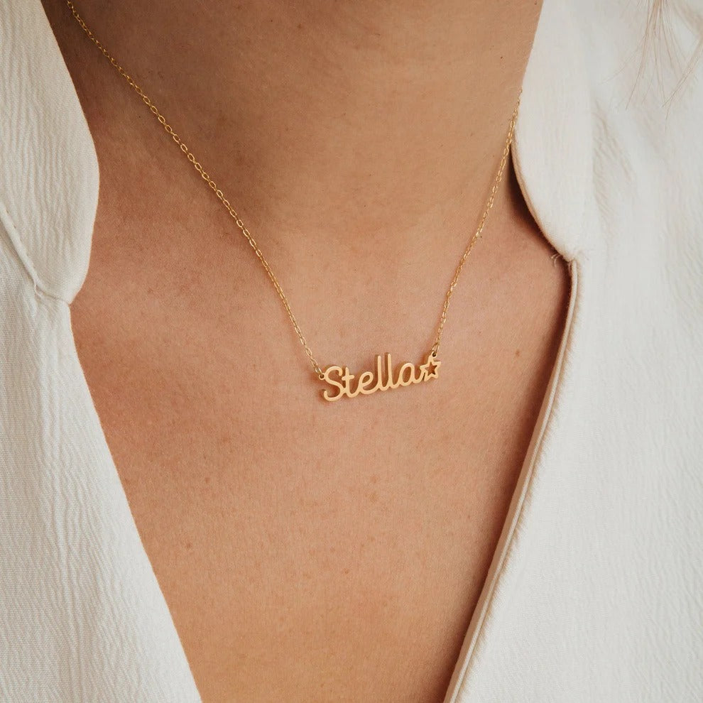 Gold necklace with 'Stellar' pendant on a person wearing a white shirt.
