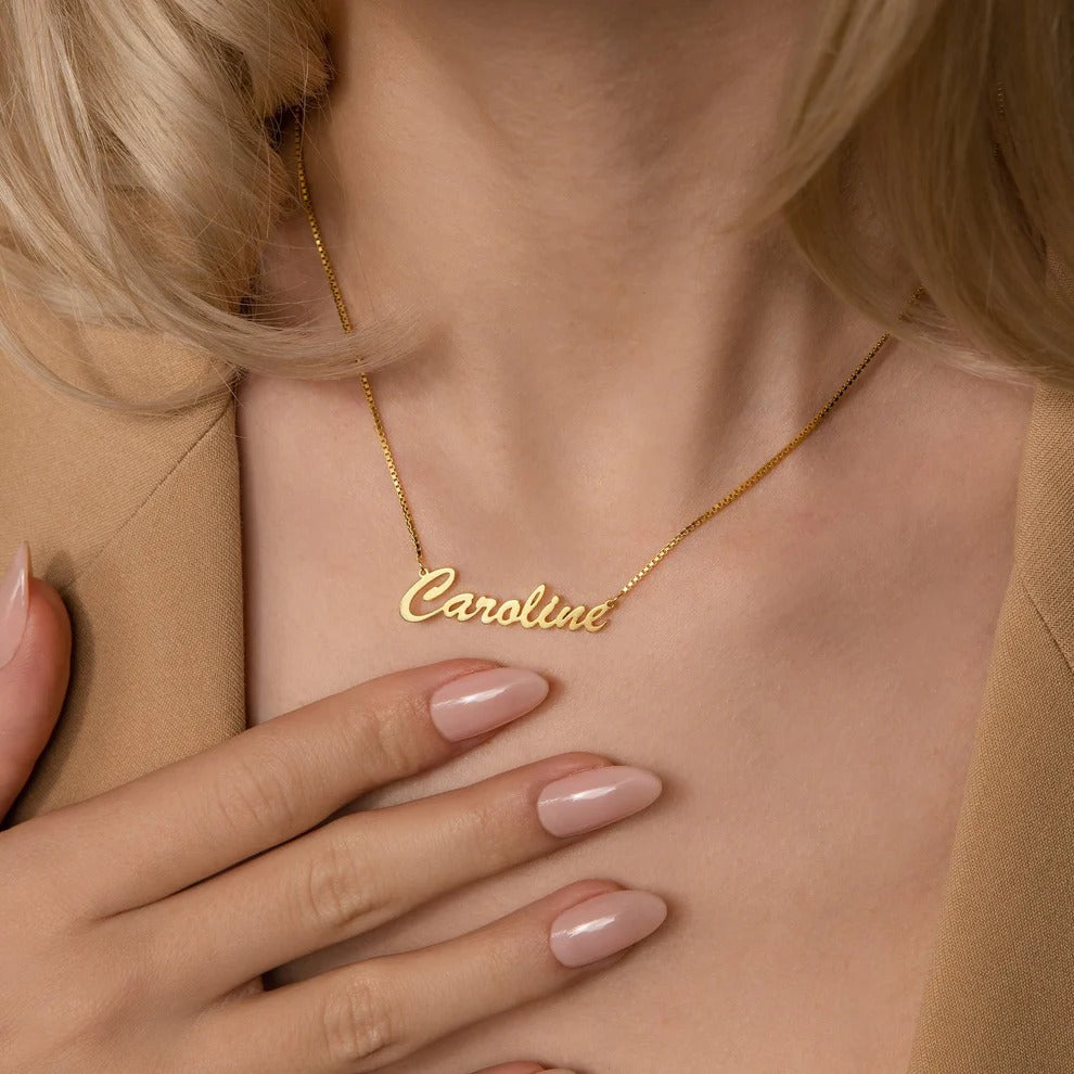 Gold name necklace with 'Caroline' on a person wearing a beige top.