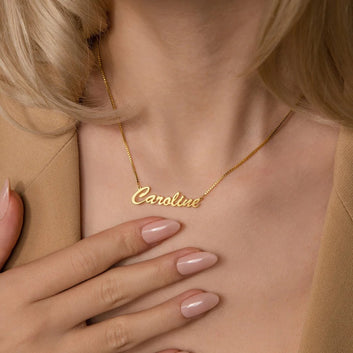 Gold name necklace with 'Caroline' on a person wearing a beige top.