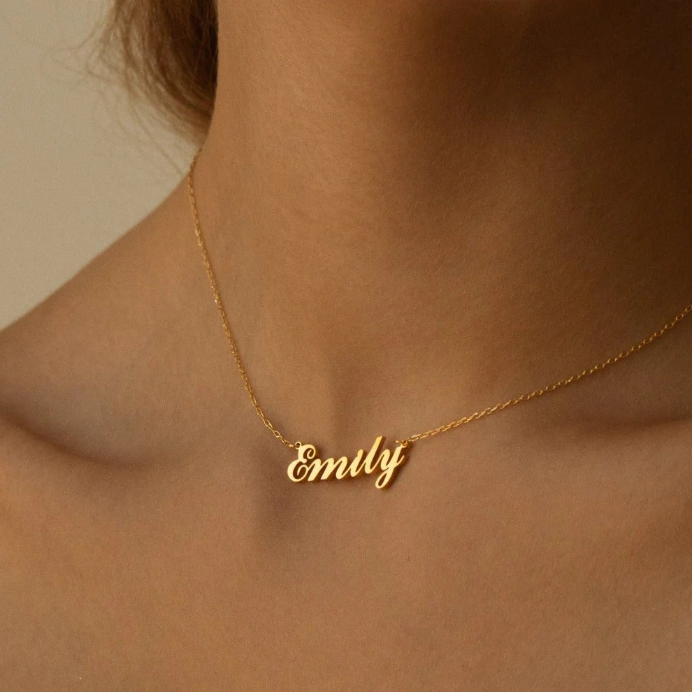 Gold necklace with 'Emily' pendant on a person's neck against a neutral background