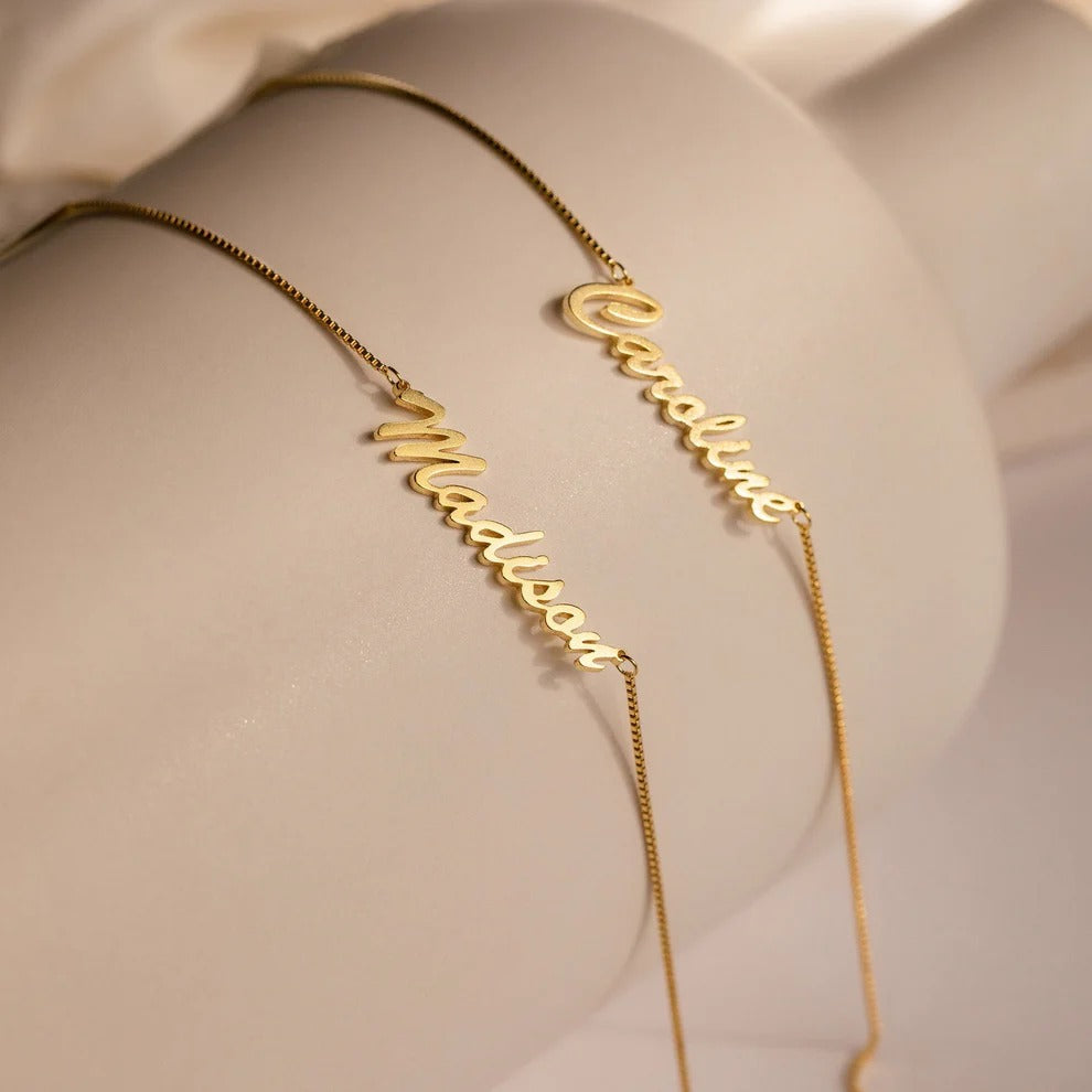 Gold name necklaces on a soft beige background