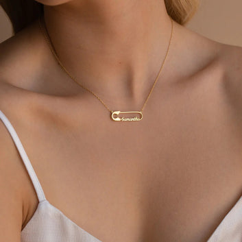 Gold necklace with a name pendant on a person wearing a white top.