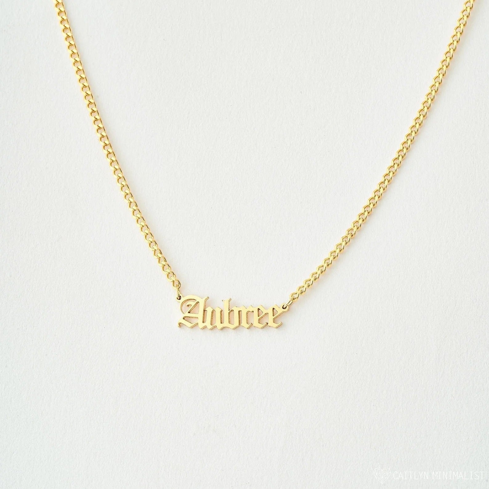 Gold necklace with 'Zahira' pendant on a light gray background