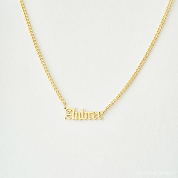 Gold necklace with 'Zahira' pendant on a light gray background