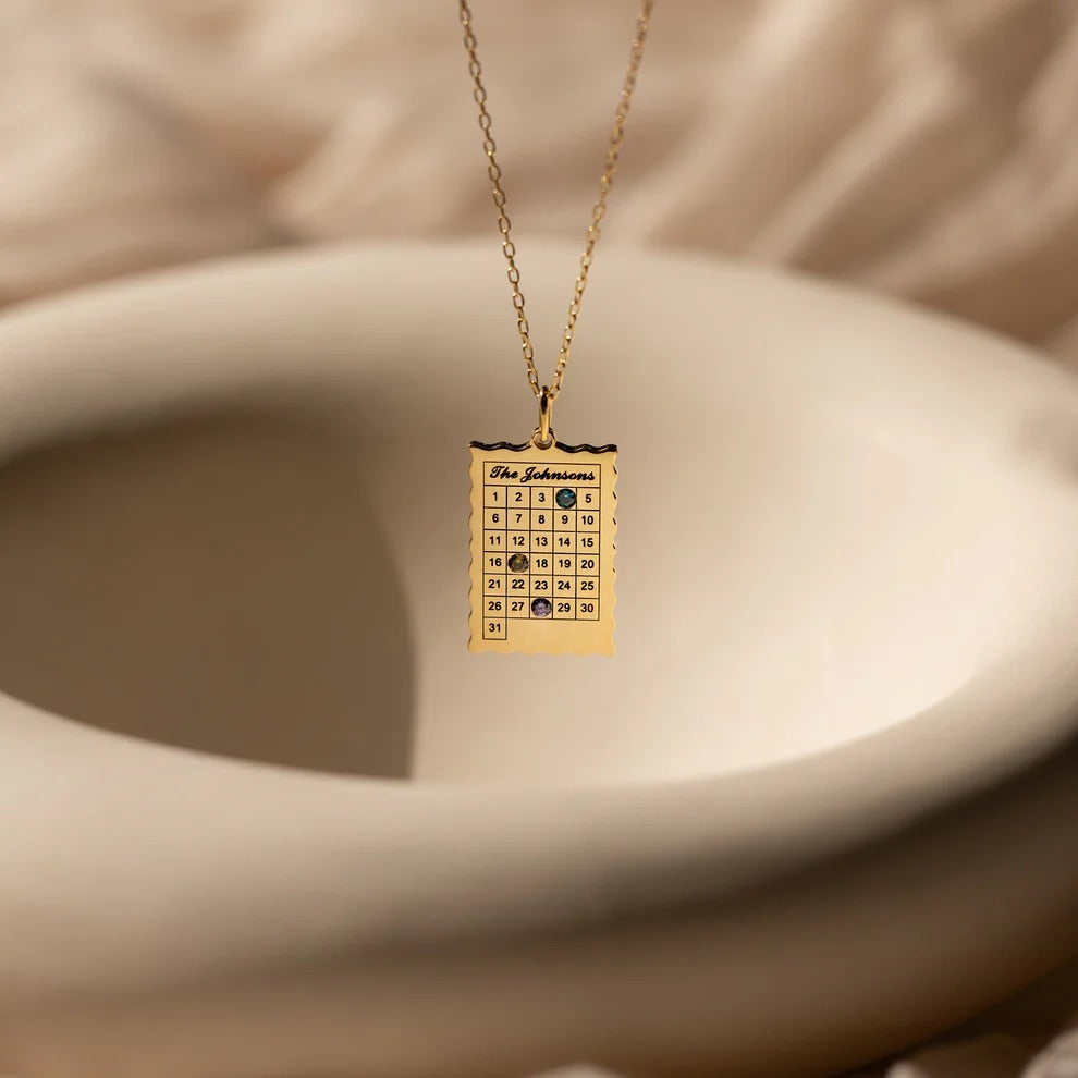 Gold necklace with a square pendant on a beige background