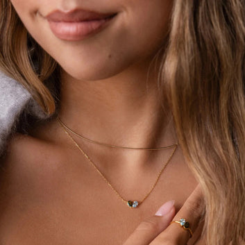 Close-up of a woman wearing a delicate gold necklace with a small pendant.