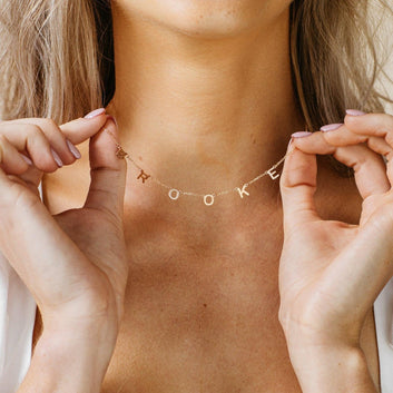 Person wearing a gold necklace with 'LOOK' pendant