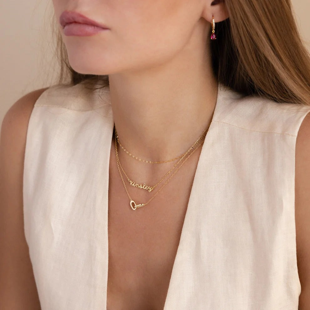 Woman wearing gold necklaces with a neutral background