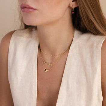 Woman wearing gold necklaces with a neutral background