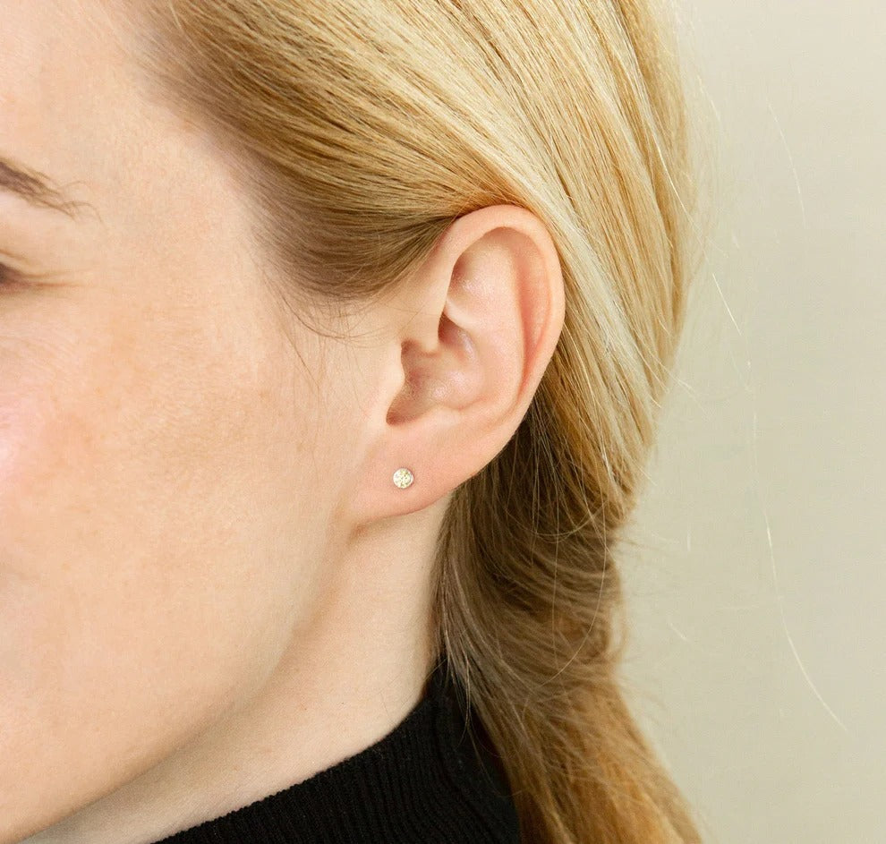 Close-up of a person wearing a small round earring.