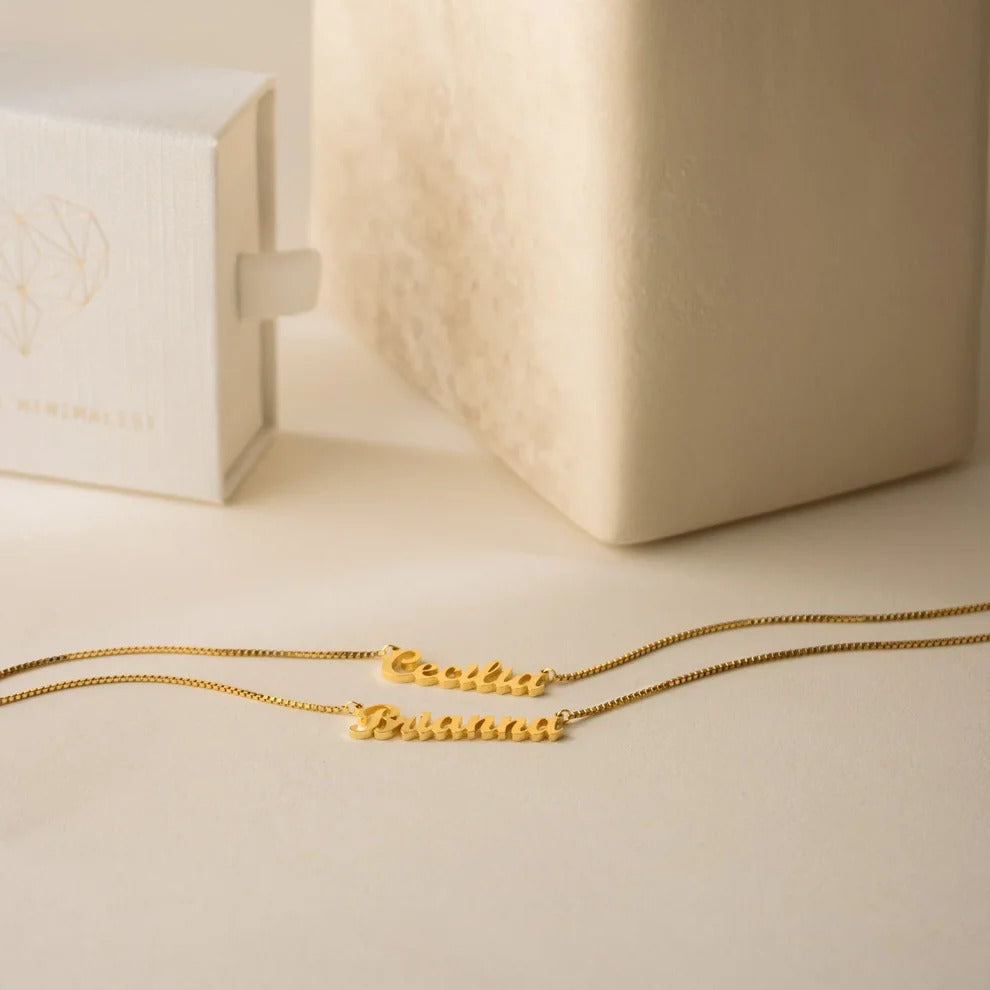 Gold necklace on a beige surface with a light wooden box in the background