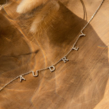 Necklace with 'AUDREY' on a wooden surface