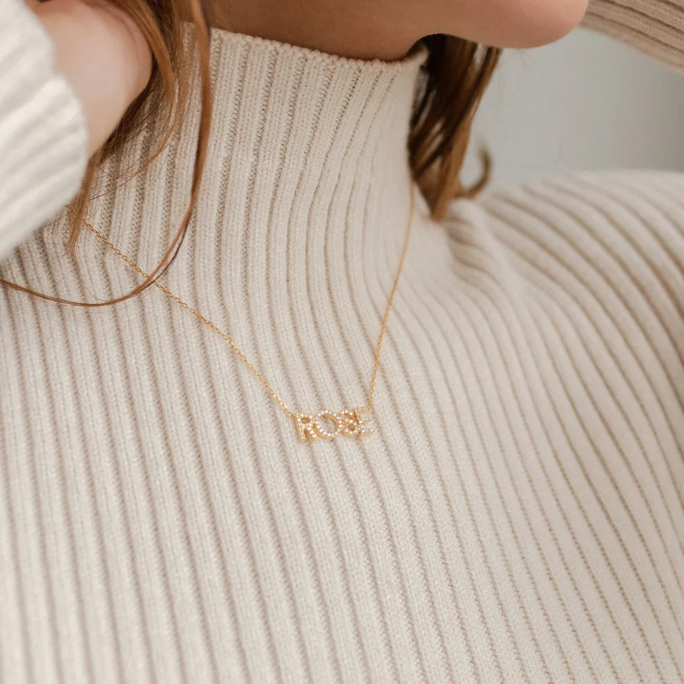 Gold necklace worn by a person in a beige sweater