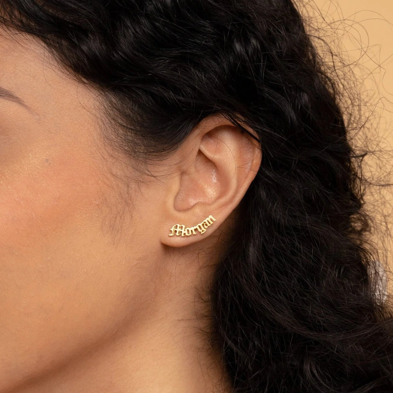 Close-up of an ear wearing a gold earring with a blurred background