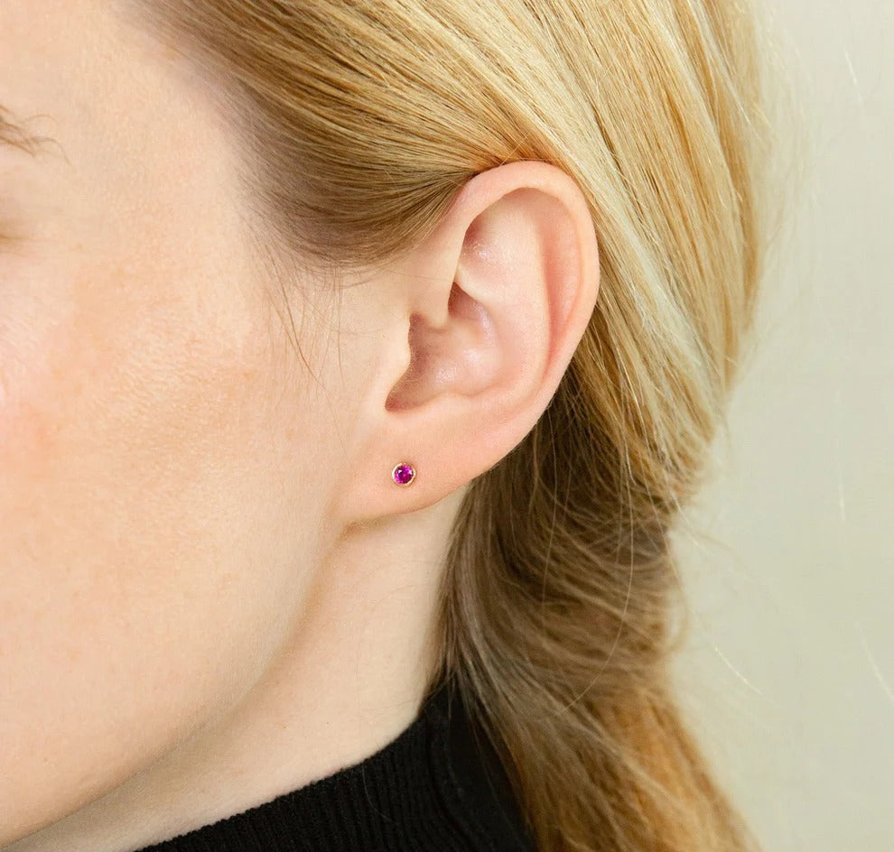 Close-up of an ear with a purple stud earring