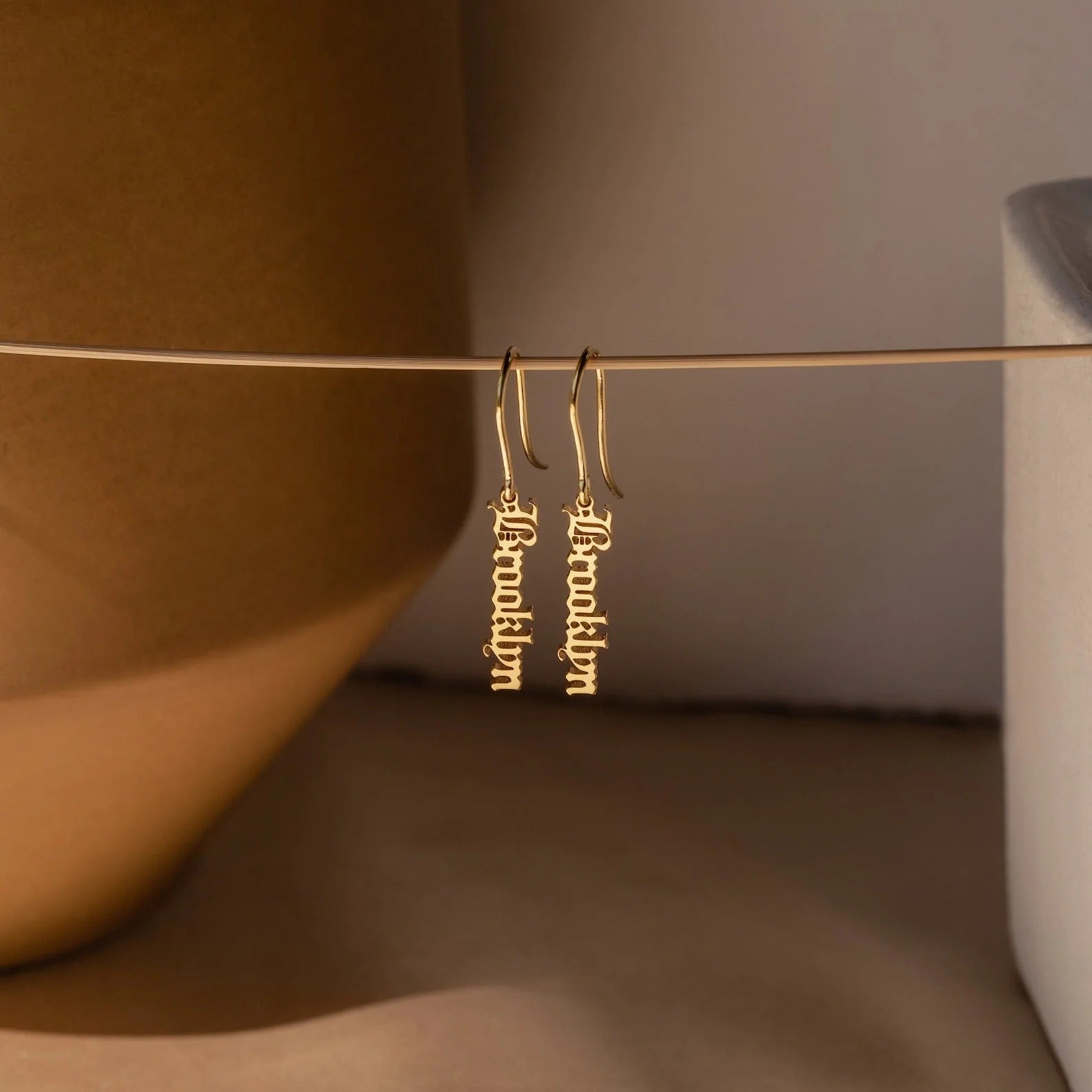 Gold earrings with 'Bella Luna' inscription on a neutral background