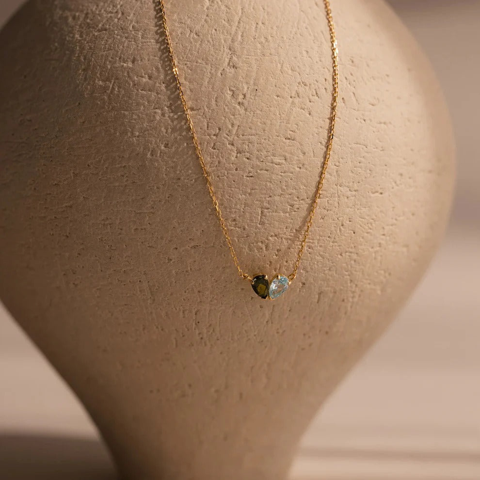 Gold necklace with two small gemstones on a mannequin bust.