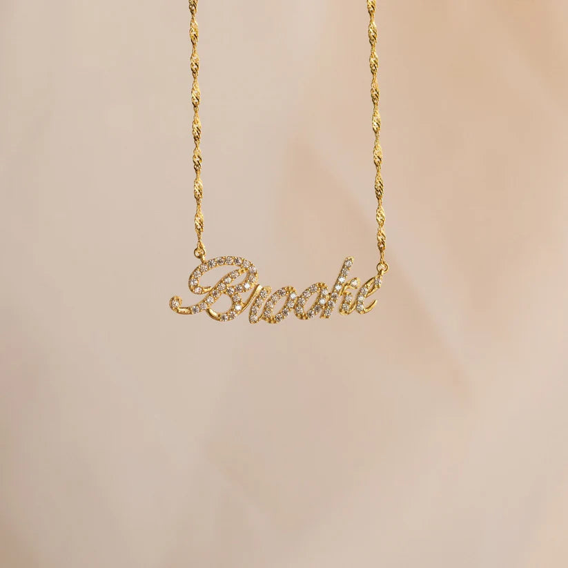 Gold necklace with 'Brooke' pendant on a beige background