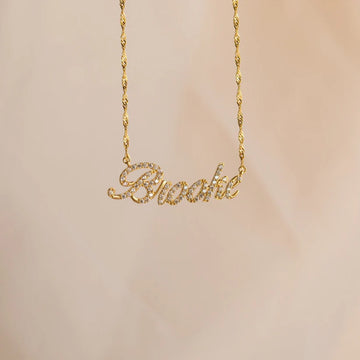 Gold necklace with 'Brooke' pendant on a beige background