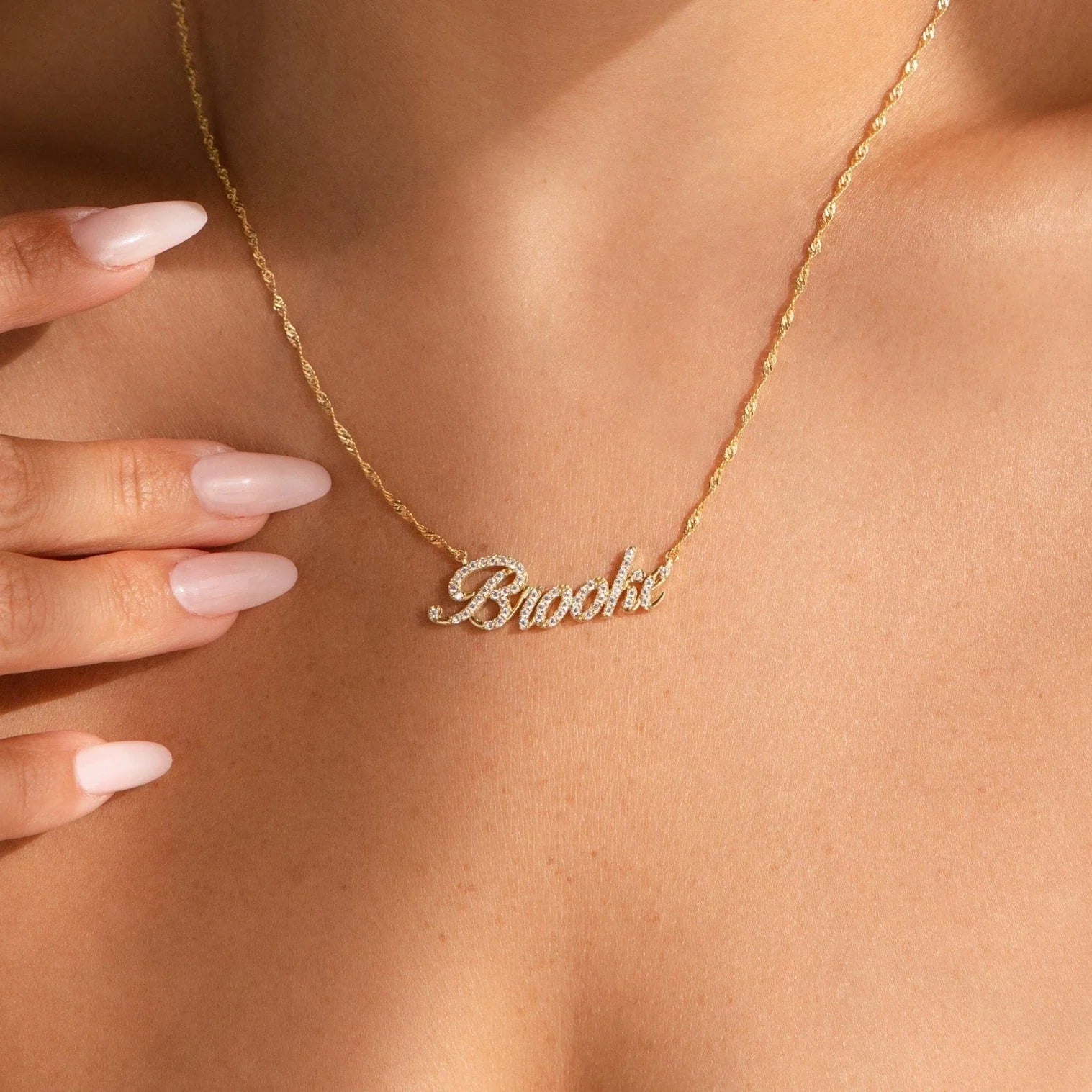 Gold name necklace on a person's neck with a blurred background
