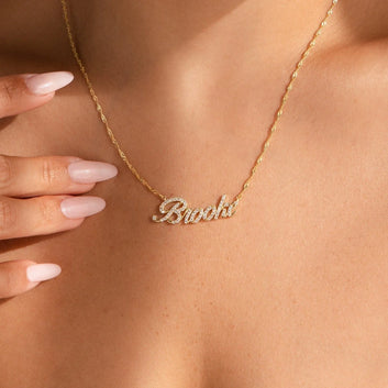 Gold name necklace on a person's neck with a blurred background
