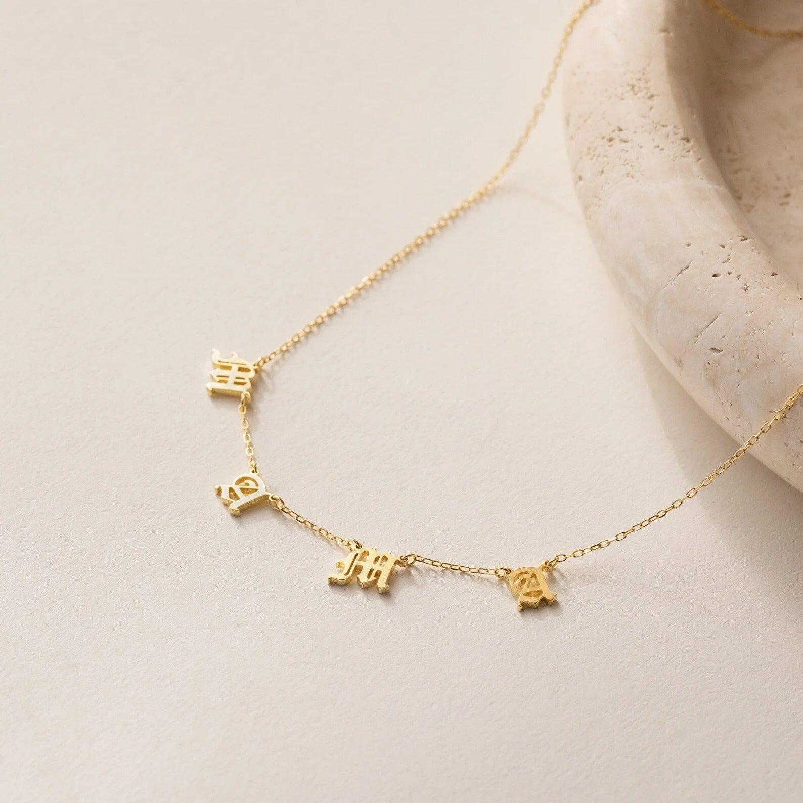 Gold necklace with small pendant on a light beige surface