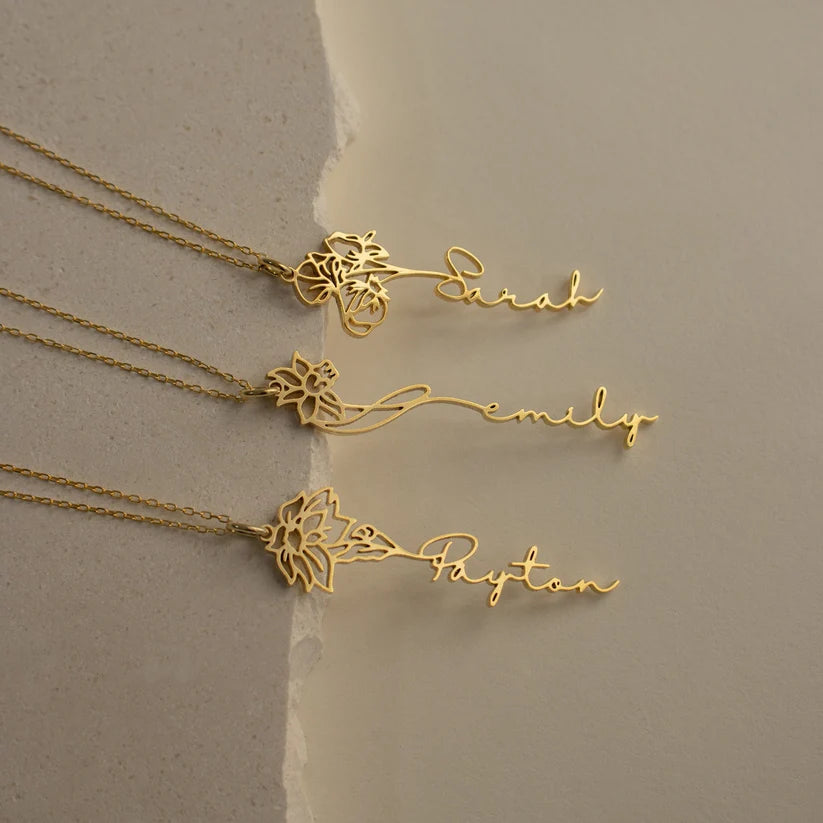 Three gold necklaces with floral designs and names on a beige background