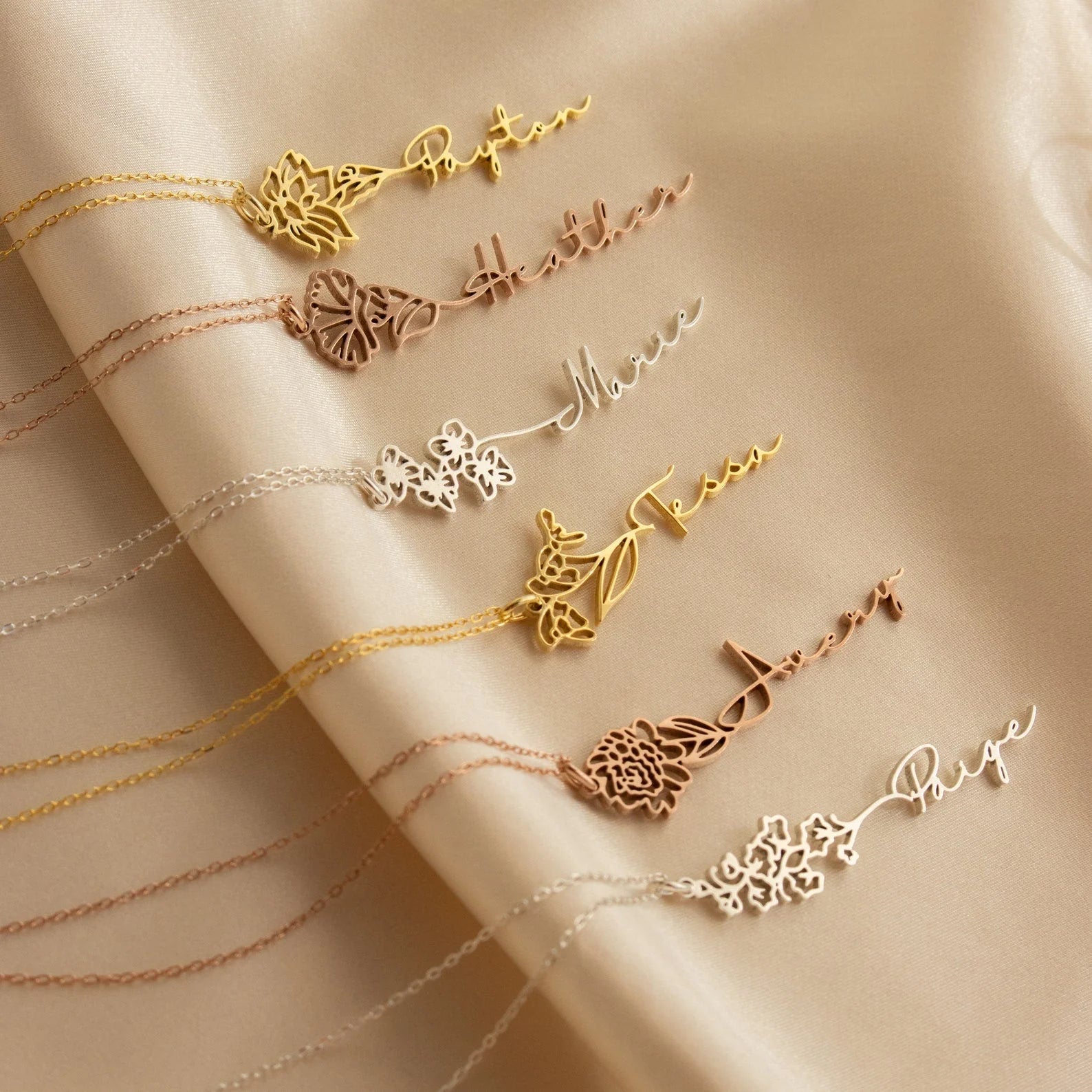 Set of gold necklaces with floral designs on a beige fabric background